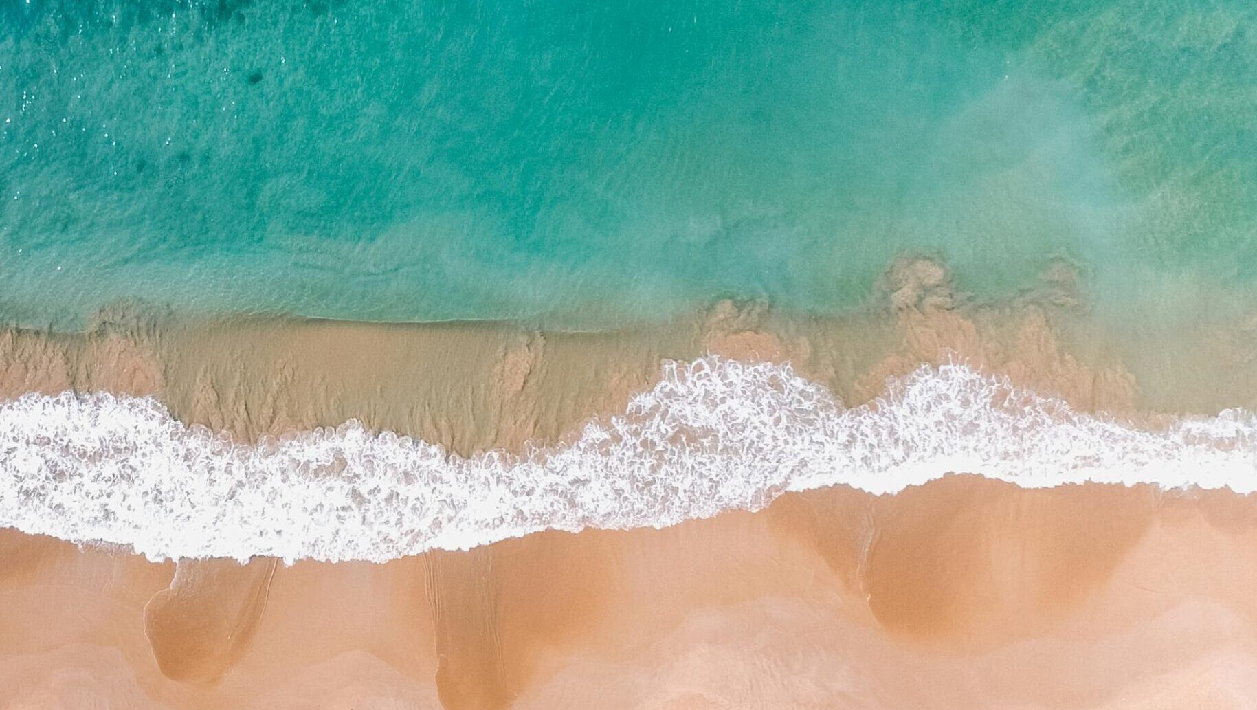 A stunning aerial shot of a beautiful beach in Dambulla, Sri Lanka with clear waters.