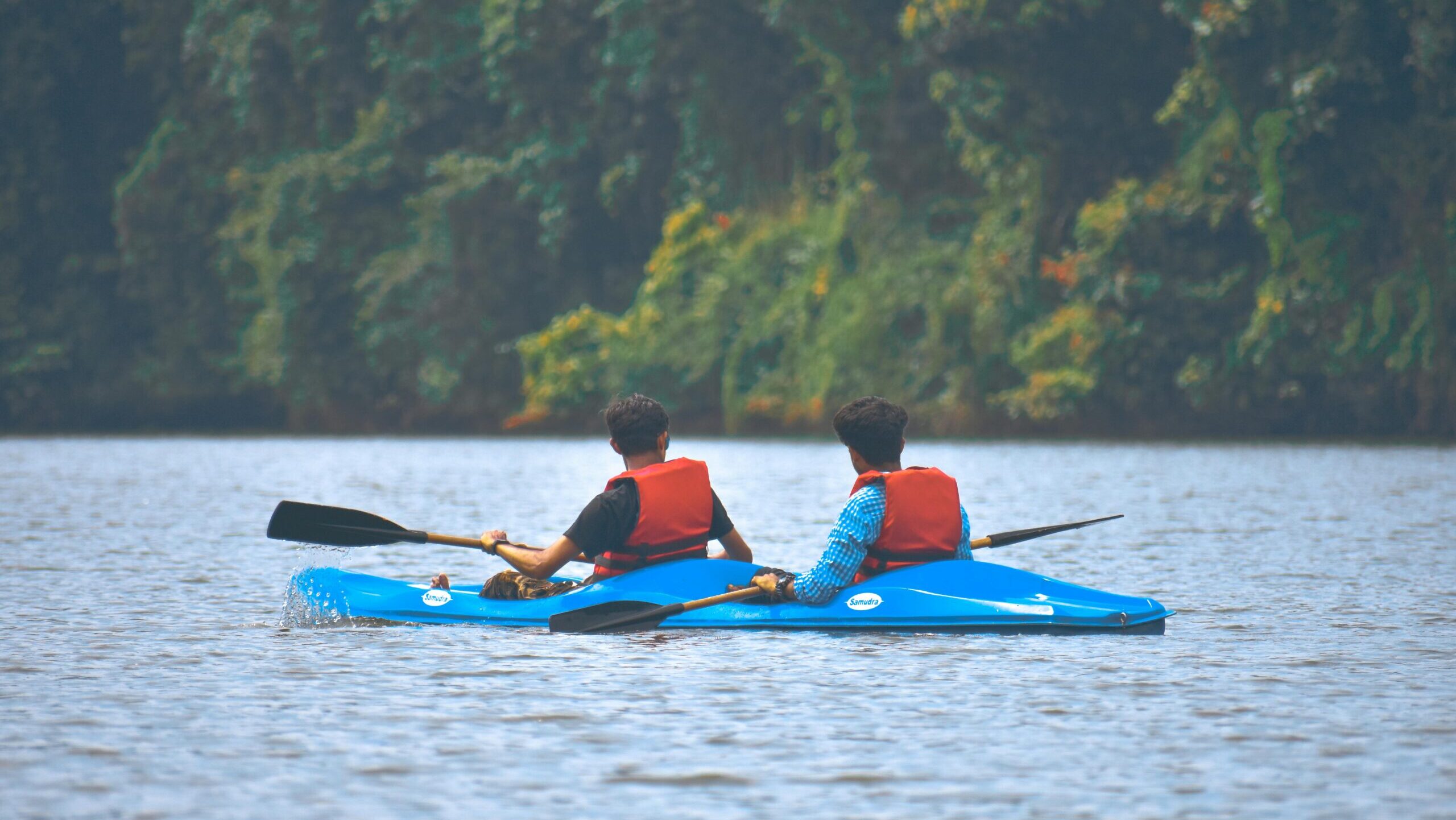 Two men enjoying a kayaking adventure on a tranquil river surrounded by lush greenery.