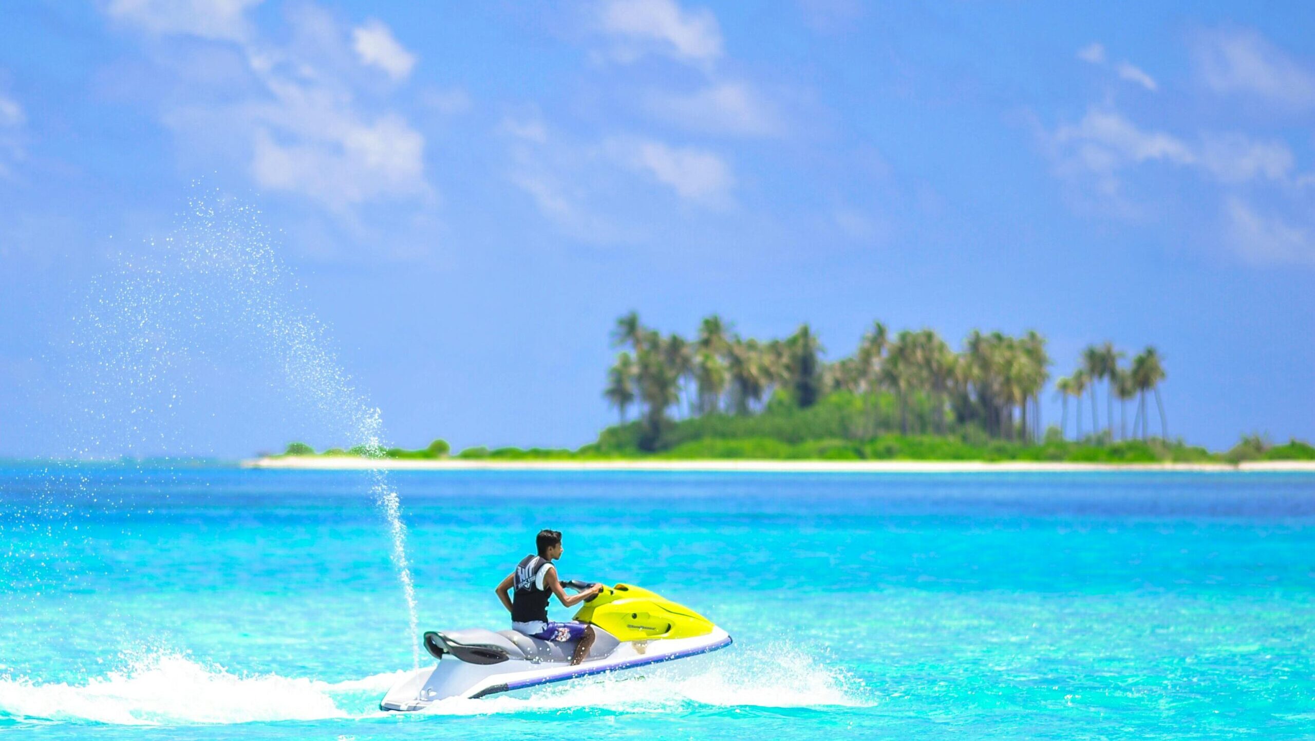 Vibrant jet ski adventure near a picturesque island in the tropical Maldives with clear blue waters and palm trees.