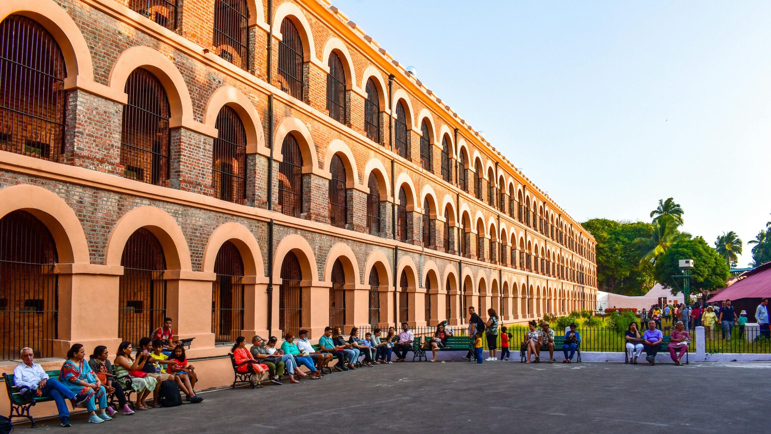 People gathered outside the historic Cellular Jail with its distinctive arched windows and barred architecture.